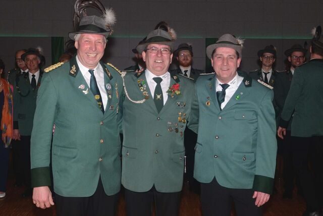 Die Hauptleute der „Jubiläumskompanien“ Hubert Köster, Vitus Bülhoff und Rüdiger Holzhüter (v.l.) stehen in der Waltroper Stadthalle. Im Hintergrund weitere Gäste der Veranstaltung.