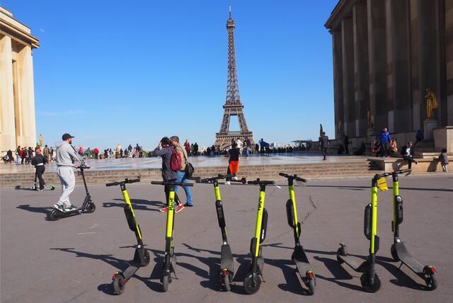 E-Tretroller stehen zum Mieten auf der Place du Trocadero bereit – im Hintergrund ist der Eiffelturm zu sehen.