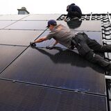 Handwerker montieren auf dem Dach eines Wohnhauses Solarmodule.
