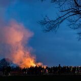 Ein Osterfeuer in Recklinghausen in der Dämmerung, davor erkennt man eine große Menschenansammlung.