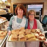 Elke Praast (l.) und Monika Kannengießer aus der Bäckerei Prang halten ein Blech mit frischen Brötchen in die Kamera