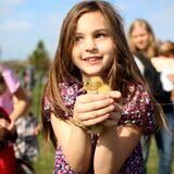 Ein Mädchen hält ein Küken in der Hand.
