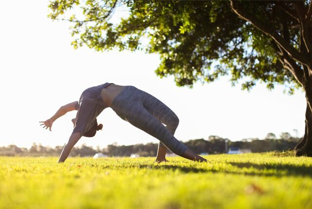 frau macht yoga übung auf einer wiese
