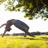 frau macht yoga übung auf einer wiese