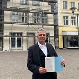 Isaac Tourgman steht auf dem Altstadtmarkt in Recklinghausen und hält die Haggada in den Händen