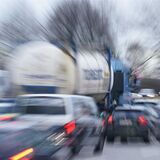 Autos und Lastwagen im Berufsverkehr im Stau auf einer mehrspurigen Straße.
