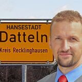 Ein Mann steht vor einem Ortsschild.
