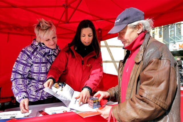 Ein Mann lässt sich an einem Infostand von zwei Frauen beraten.