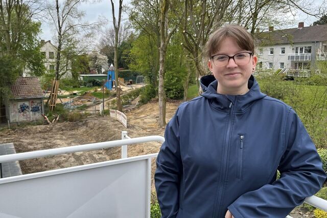 Michelle Marcus lächelt in die Kamera. Im Hintergrund ist ein Spielplatz und eine große Baustelle zu erkennen.