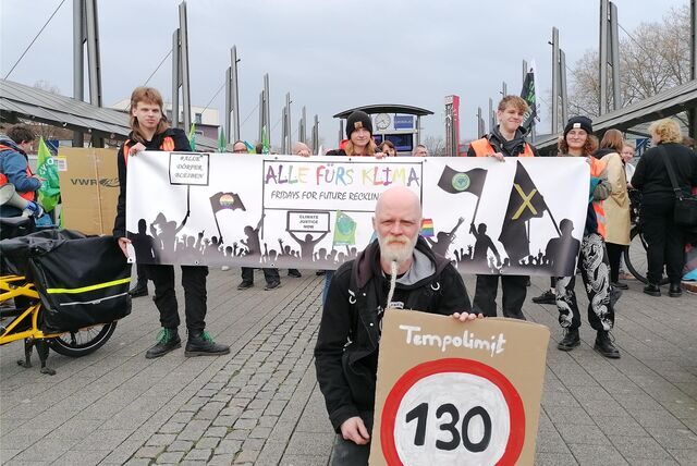 Im Hintergrund drei Aktivisten von „Fridays for Future“ mit einem Banner auf dem Europaplatz in Recklinghausen, vorne Peter Gerwinat von „Parents For Future“.