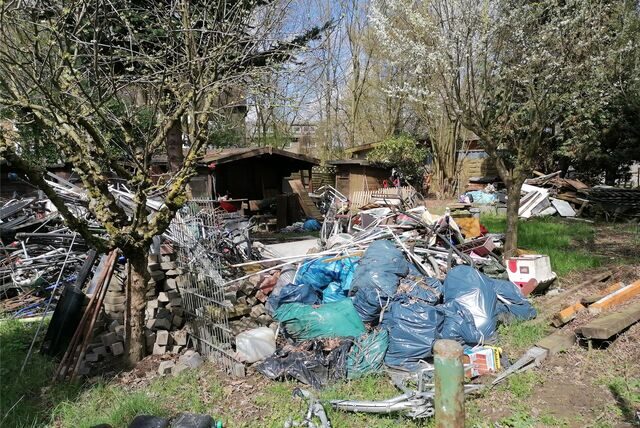 Zu sehen ist ein Schrebergarten der voller Müll- und Schrottbergen ist,