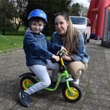 Ein Kind sitzt auf einem Tretfahrrad, dahinter hockt die Mutter
