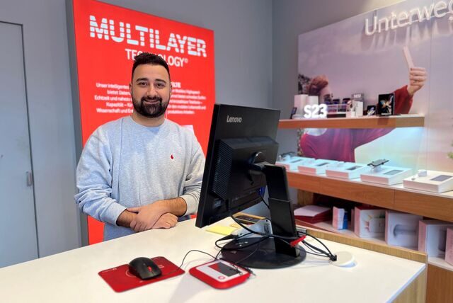 Ein Mann steht in einem Vodafone-Shop hinter einem Schalter