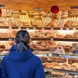 Zwei Menschen stehen vor einer Auslage in einer Bäckerei.