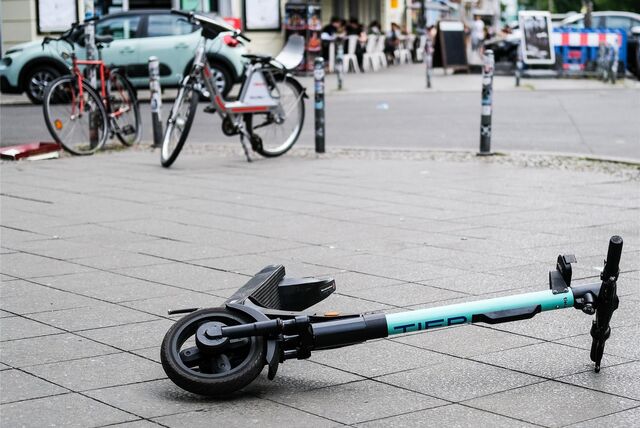 Ein E-Scooter liegt umgekippt mitten auf dem Gehweg.
