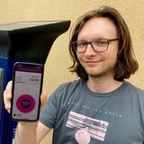 DM-Redakteur Benjamin Kübart steht mit einem Smartphone in der Hand vor einem Parkticket-Automaten.