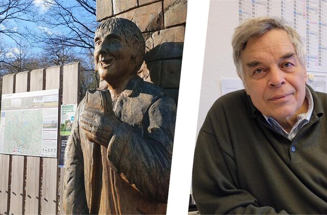 Eine Figur aus Holz steht an einem Wanderparkplatz, daneben ein Mann