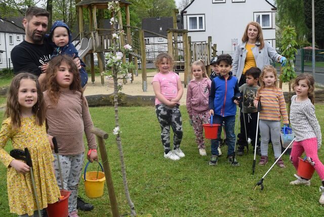 Kinder posieren bei einer Müllsammelaktion auf einem Spielplatz.
