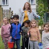 Kinder posieren bei einer Müllsammelaktion auf einem Spielplatz.