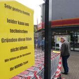 Ein gelbes Schild weist auf die verschobene Eröffnung von Norma hin.