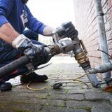 Ein Mitarbeiter eines Diesel- und Heizöl-Unternehmens befestigt die Zapfpistole an einem Füllstutzen für die Heizöllieferung an einen Kunden in einem Einfamilienhaus.