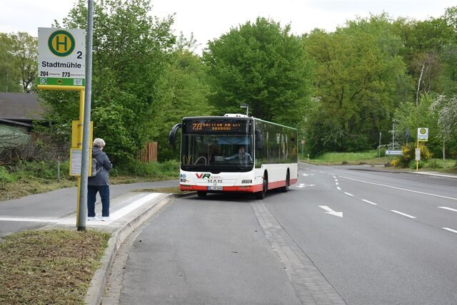 Eine Frau wartet an der Bushaltestelle auf den nahenden Bus.
