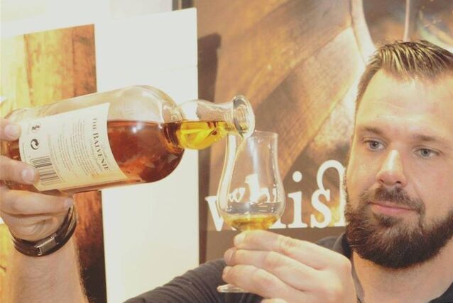 Spirituosen-Experte Sebastian Büssing schüttet aus einer Flasche eine goldene Flüssigkeit in ein Glas.