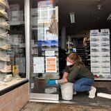 Sabrina Sojka-Berg, Mitarbeiterin des Schuhgeschäftes „Schuh-House“ in Recklinghausen, reinigt das Schaufenster mit Schwamm und Wasser. Am Fenster sind Kotspuren zu erkennen.