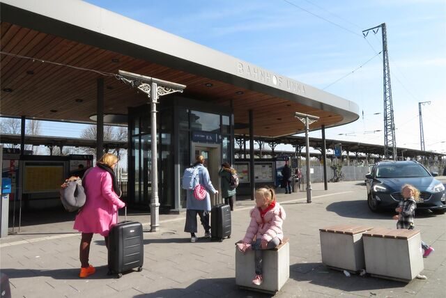 Menschen mit Koffer warten vor dem Bahnhof in Unna.