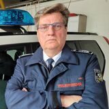 Ein Mann steht vor einem Feuerwehrfahrzeug.