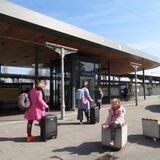 Menschen mit Koffer warten vor dem Bahnhof in Unna.