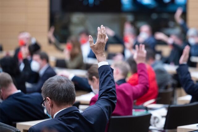 Landtagsabgeordnete halten während einer Abstimmung bei einer Sondersitzung des Landtags Baden-Württemberg zur Corona-Politik die Hände nach oben.