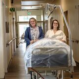 Ewa Monika Janocha und Stefanie Gross-Ulrich schieben ein Bett über den langen Krankenhaus-Flur.
