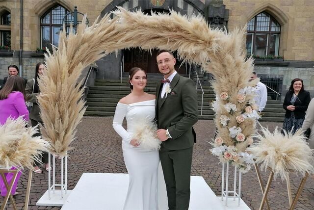 Zu sehen ist eine Braut und ein Bräutigam vor dem Rathaus.