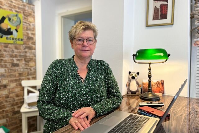 Ursula Wenig steht am Empfangstresen von ihrem Reisebüro. Vor ihr steht ihr Laptop und die Telefone liegen in Reichweite.