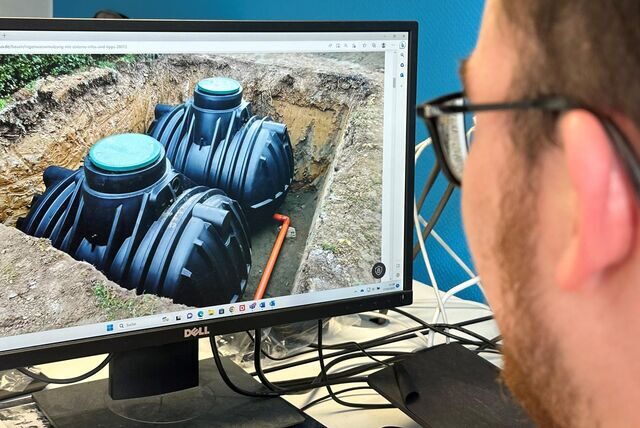 Ein Mann schaut auf einen Monitor, auf dem eine Regenwasserzisterne zu sehen ist.
