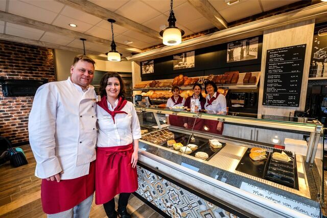Mehrere Personen in weißen Hemden und roten Schürzen stehen im Ladenlokal der Bäckerei Bomheuer in Recklinghausen.