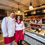 Mehrere Personen in weißen Hemden und roten Schürzen stehen im Ladenlokal der Bäckerei Bomheuer in Recklinghausen.