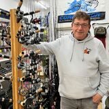 Olaf Wiemann steht in seinem Angelgeschäft in Recklinghausen. Er lächelt in die Kamera. Neben ihm sind Angelruten und weiteres Zubehör zu erkennen.
