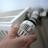 Links eine Hand, die am Thermostat einer Heizung dreht, rechts Heizungsexperte Andreas Rawe aus Recklinghausen