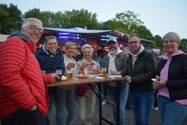 Menschen stehen auf einer Party um einen Stehtisch herum.