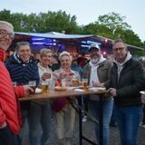 Menschen stehen auf einer Party um einen Stehtisch herum.