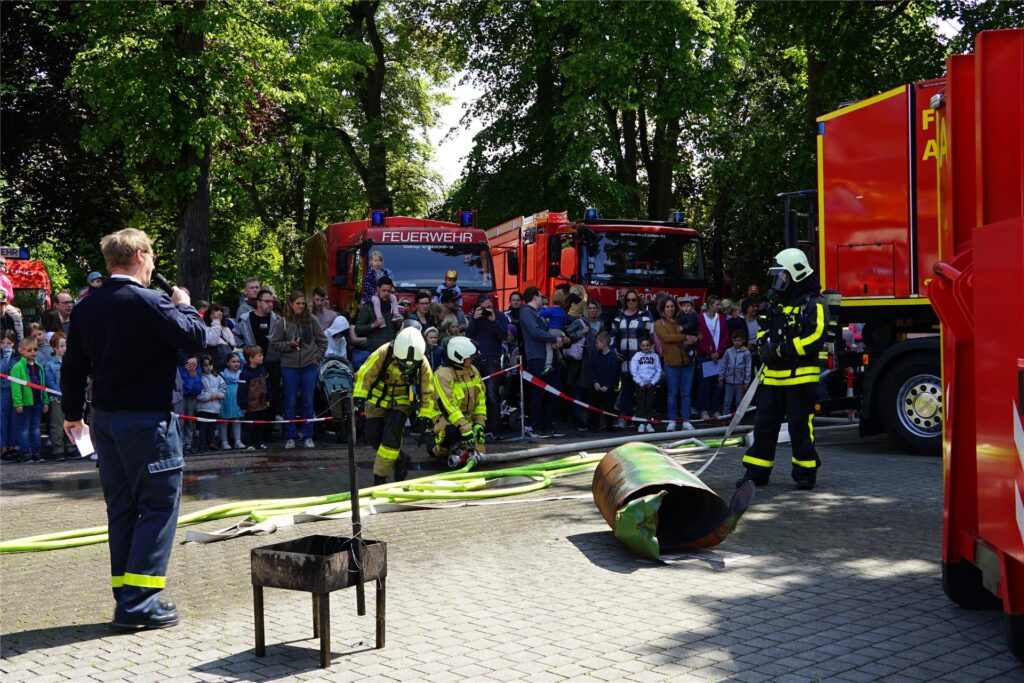 Vier Feuerwehrleute demonstrieren, wie ein Feuer gelöscht wird.