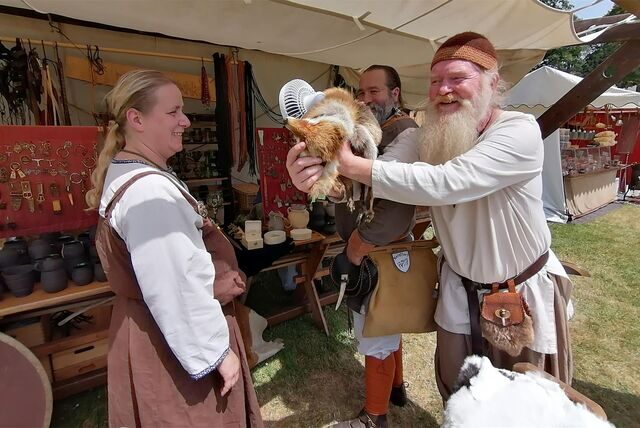 Mittelalterlich gekleidete Menschen mit einem ausgestopften Tier vor einem Stand.