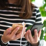 Eine Frau hält ein Smartphone in der einen und eine damit verbundene Powerbank in der anderen Hand.