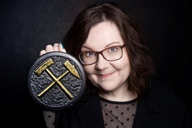 Sabine Bode hält ein Symbol aus dem Bergbau in der Hand.