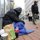 Ein Obdachloser sitzt in der Fußgängerzone.