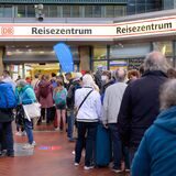 Reisende stehen vor einem Reisezentrum der Deutschen Bahn.