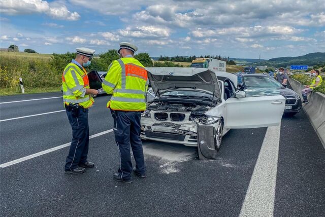 Polizisten stehen neben einem Unfallwagen.