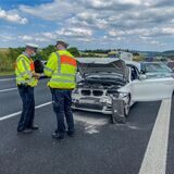 Polizisten stehen neben einem Unfallwagen.